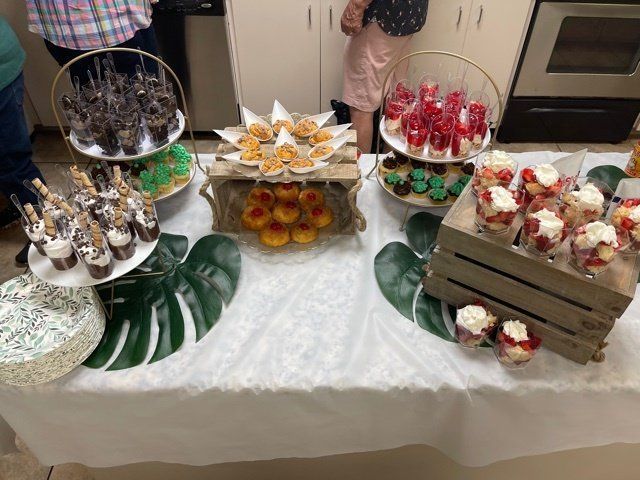 Dessert buffet on a table with cupcakes, fruit parfaits, and other treats.