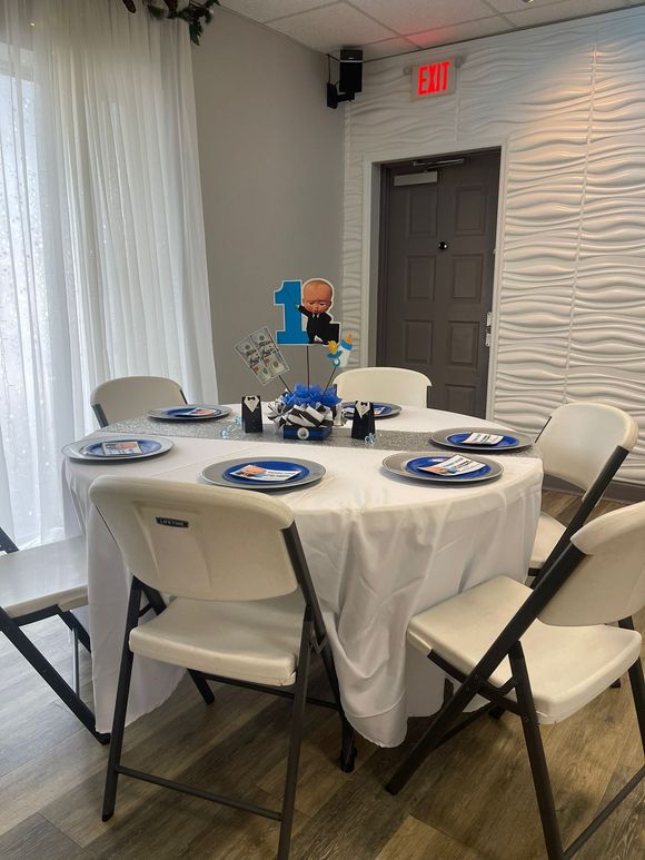 A round table set for a Boss Baby-themed party with white chairs.