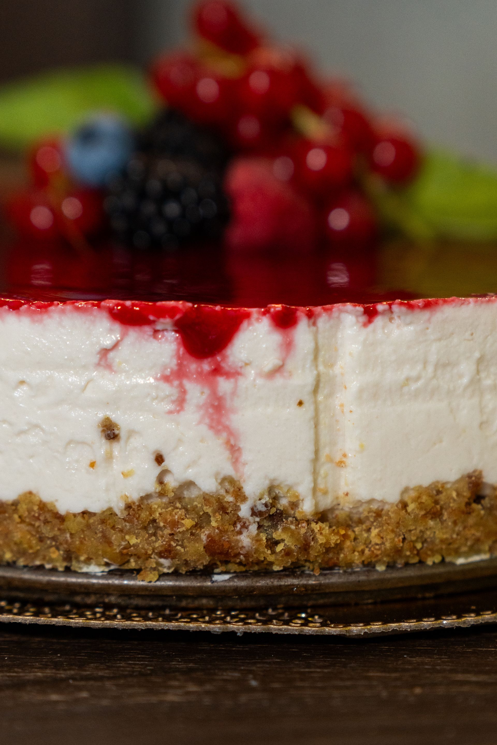 Fetta di cheesecake con guarnizione di frutti di bosco e salsa rossa che cola lungo i lati