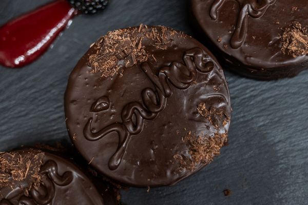 Biscotti al cioccolato farciti su una superficie di ardesia scura, uno dei quali reca la scritta 