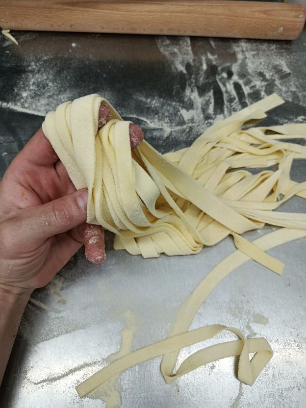 In una cucina, delle mani modellano delle palline di pasta arancione su carta da forno.