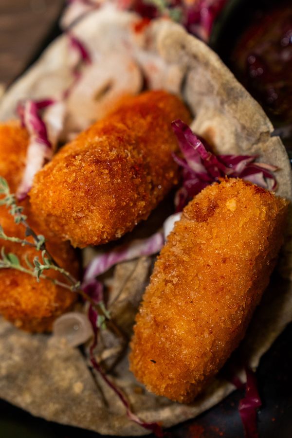 Taco di pane di mais con due crocchette fritte dorate e cavolo viola su un piatto
