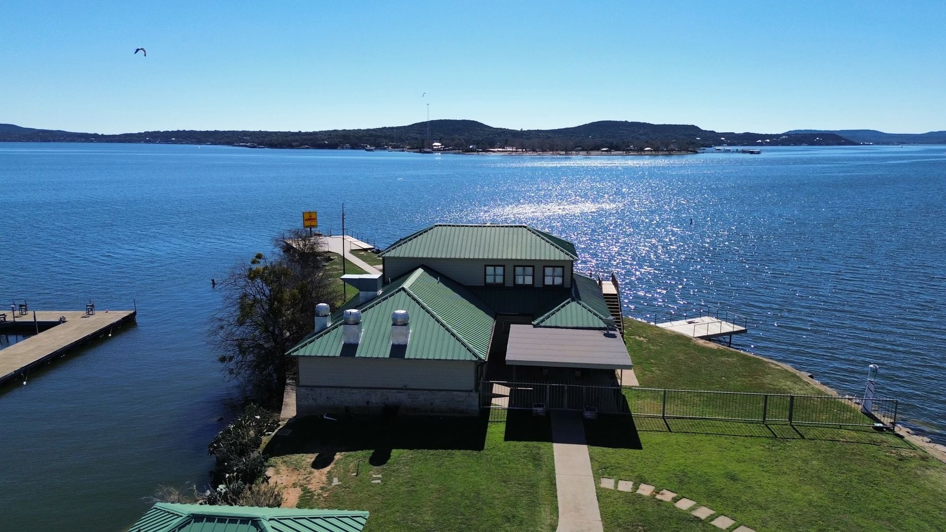 An aerial view of a house on a small island in the middle of a lake.