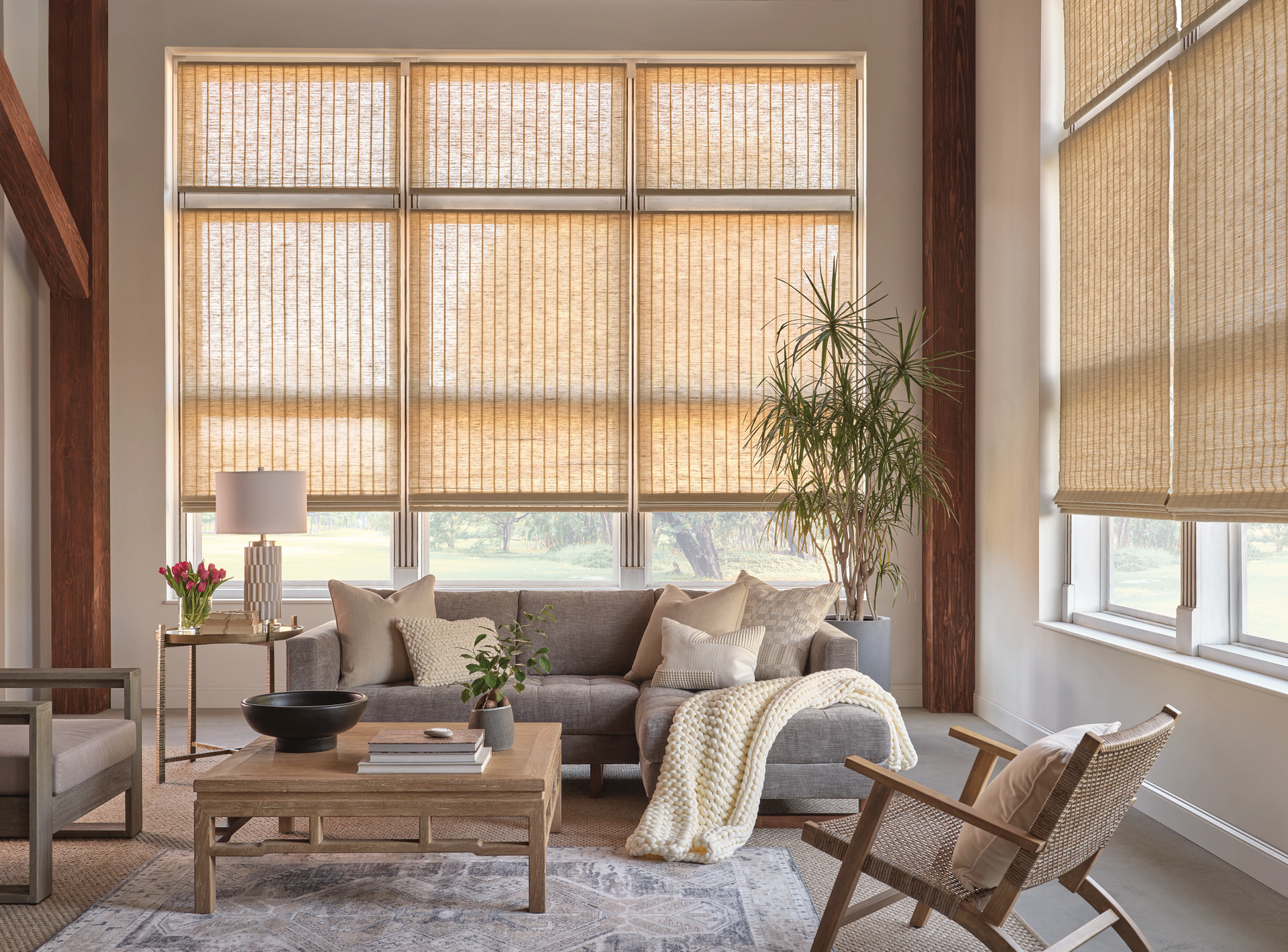 Cozy sunlit living room with bamboo blinds, neutral sofa, coffee table, and woven chair