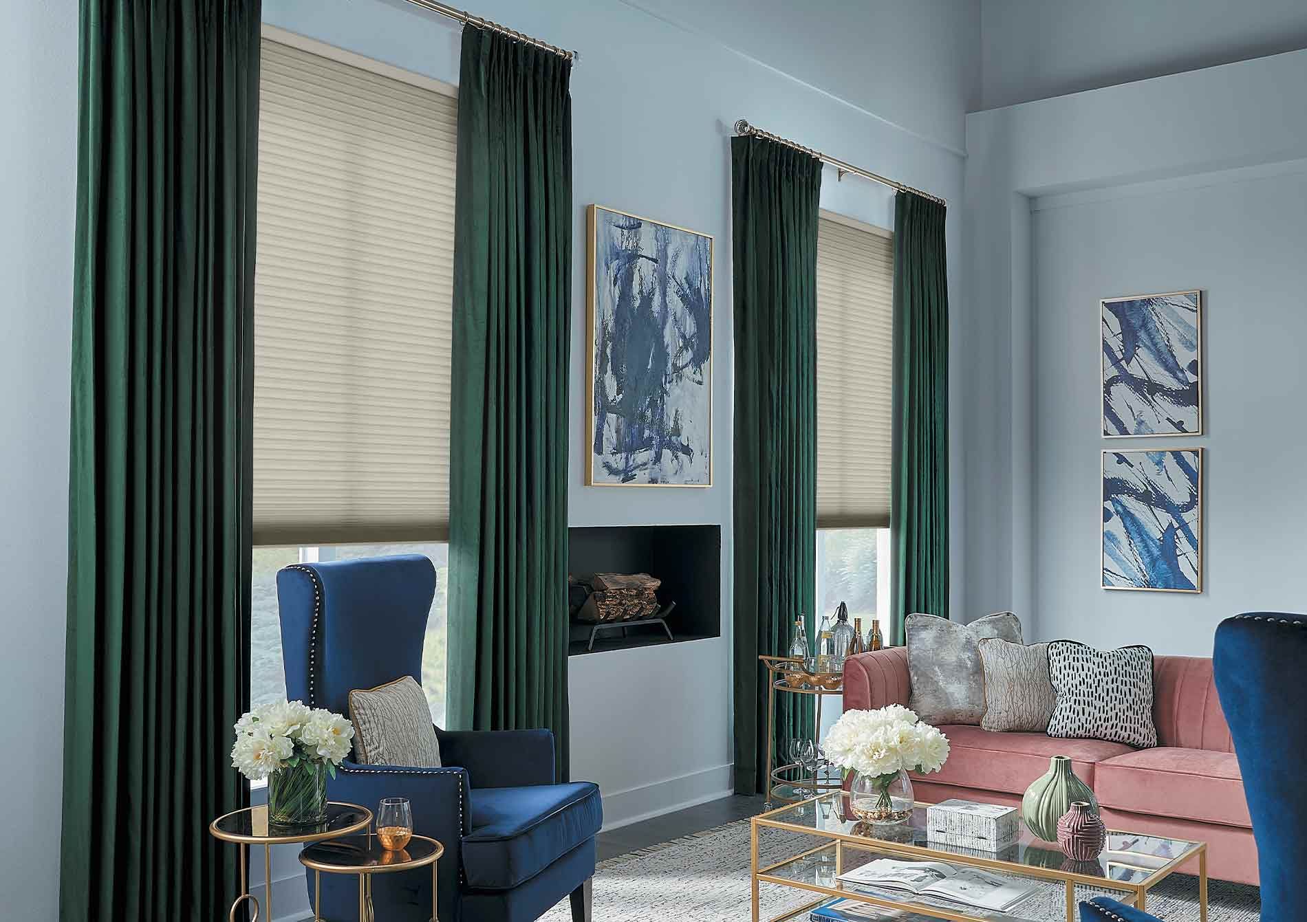 Bright living room with blue chairs, pink sofa, tall windows, and floral decor