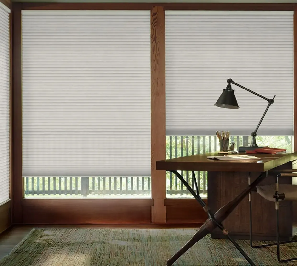 Minimal home office with wooden desk, black lamp, and white blinds covering large windows.