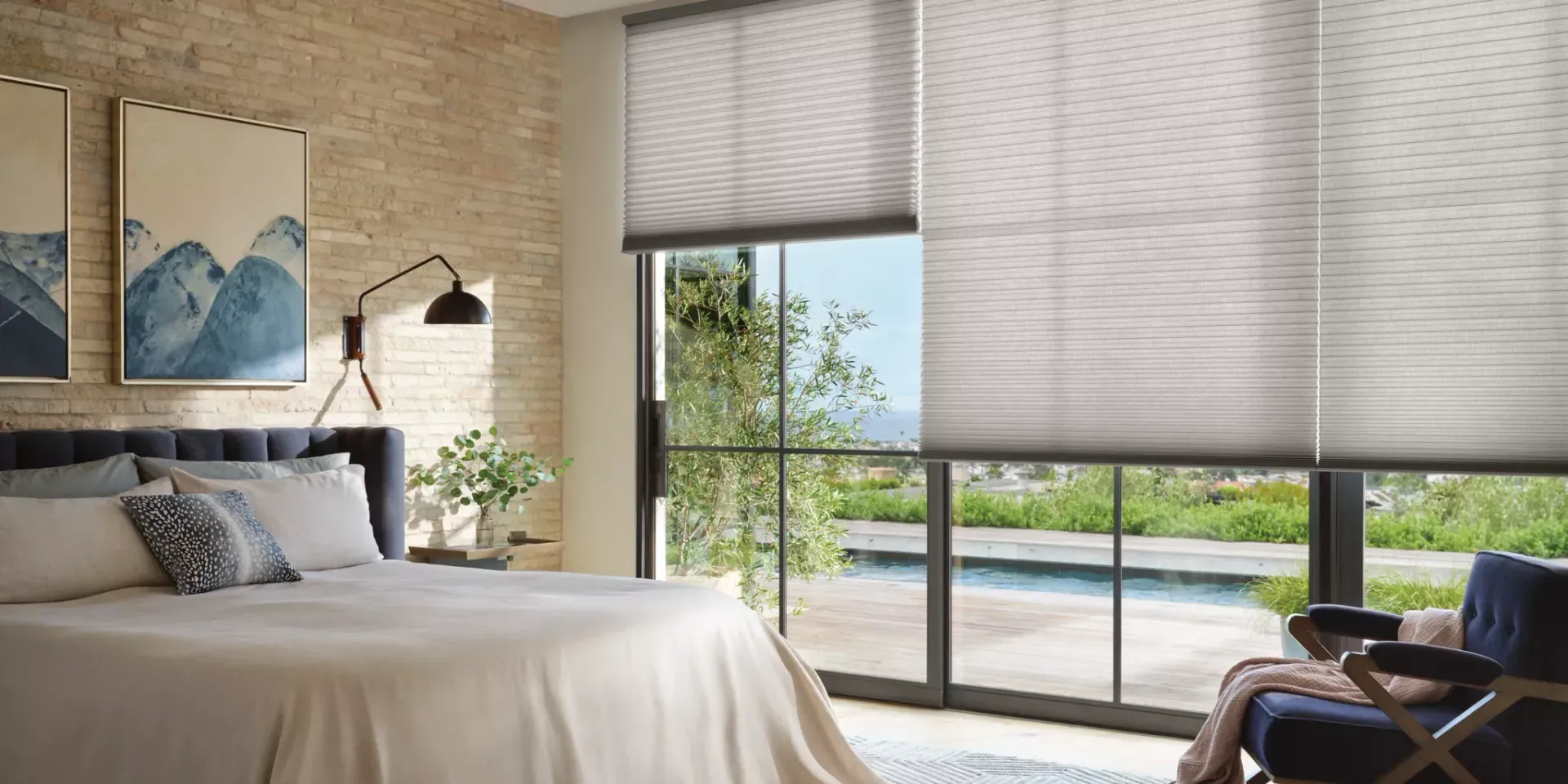 Bright bedroom with a large bed, balcony view, and a chair by the window in natural light
