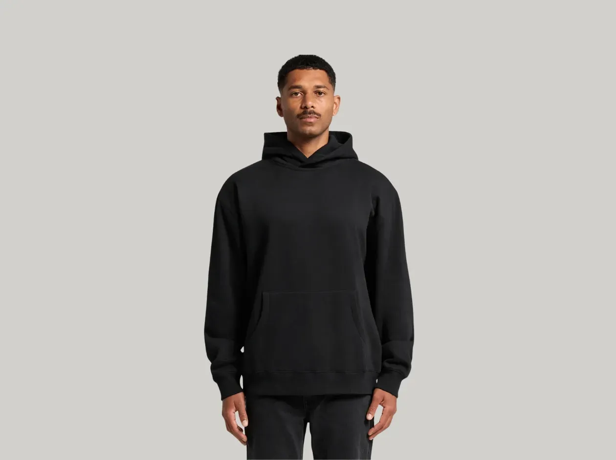 Person wearing a black hoodie and black pants against a light gray background
