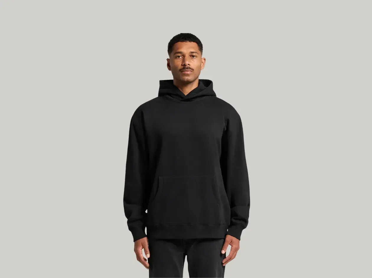 Person wearing a black hoodie and black pants against a light gray background