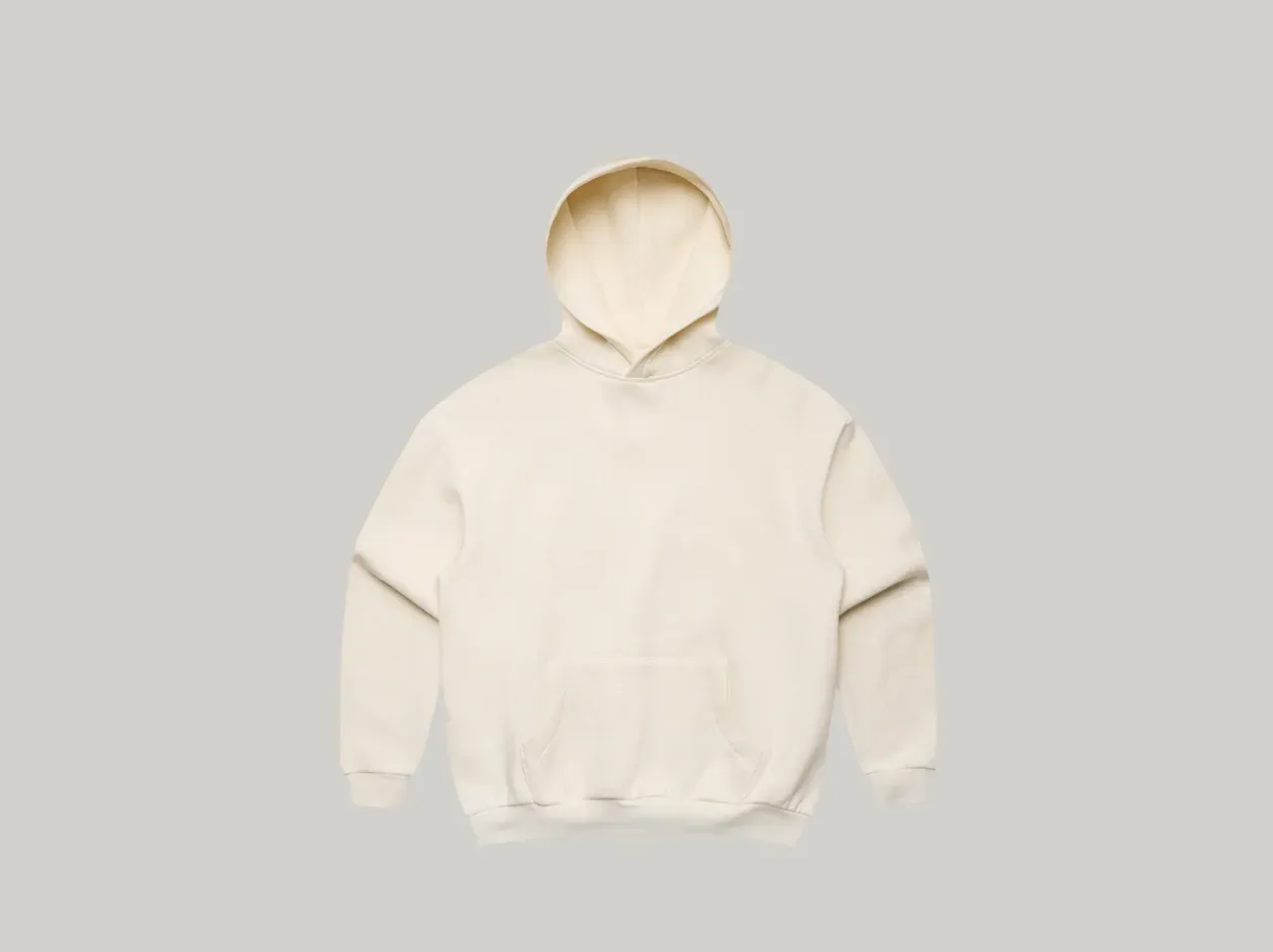 Person standing against a light gray background wearing a cream hoodie and black pants