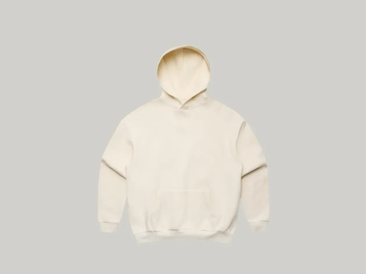Person standing against a light gray background wearing a cream hoodie and black pants