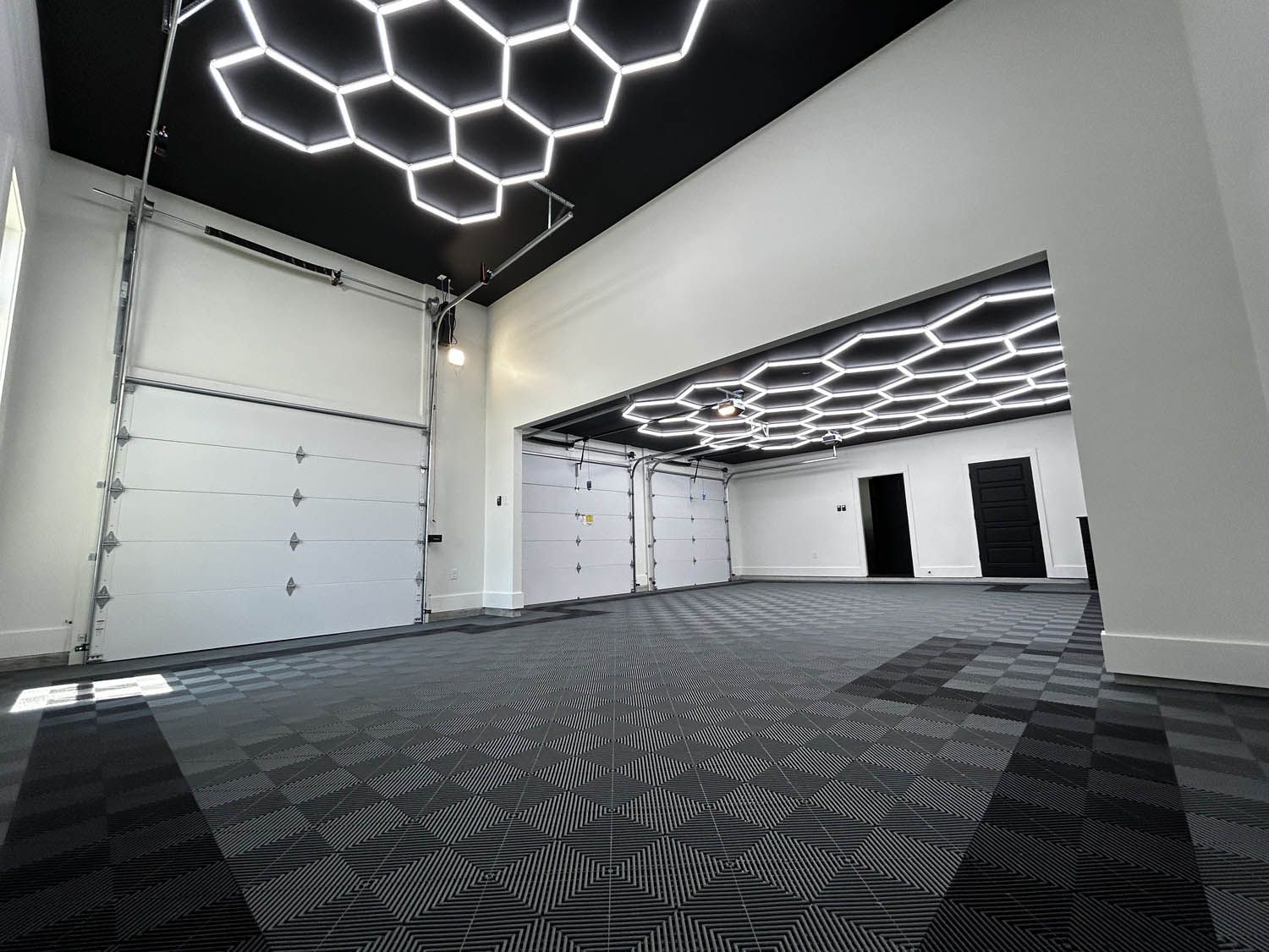 Spacious, modern garage interior with black and white hexagonal ceiling lights and patterned floor tiles.