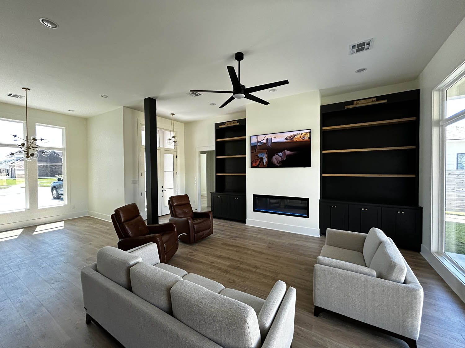 Spacious living room with tan flooring, white walls, and dark built-in shelves flanking a fireplace and TV.