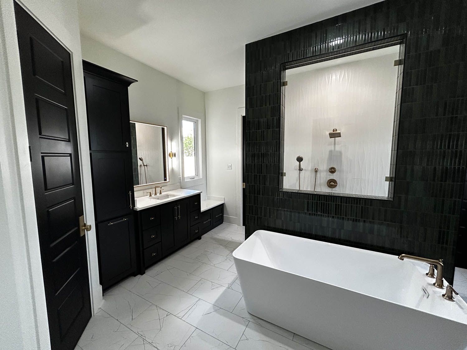 Modern black and white bathroom with a tub, dark cabinets, and a large mirror.
