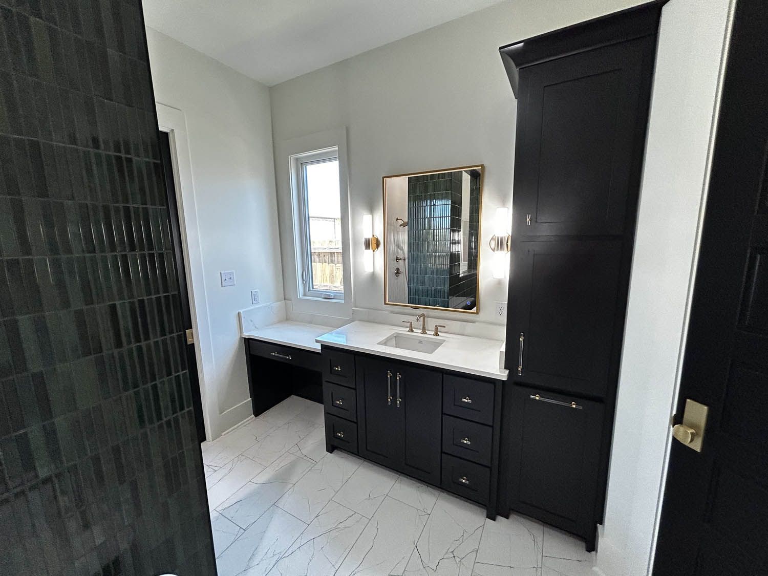 Bathroom with dark cabinetry, white countertops, and black tile shower.