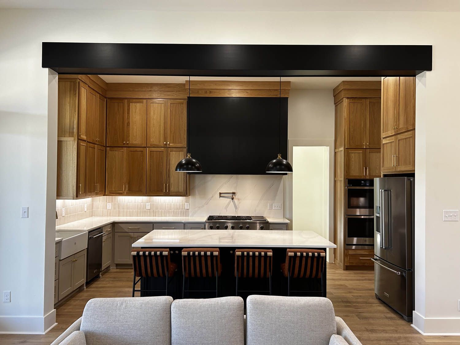 Kitchen interior with wood cabinets, island, and black range hood.