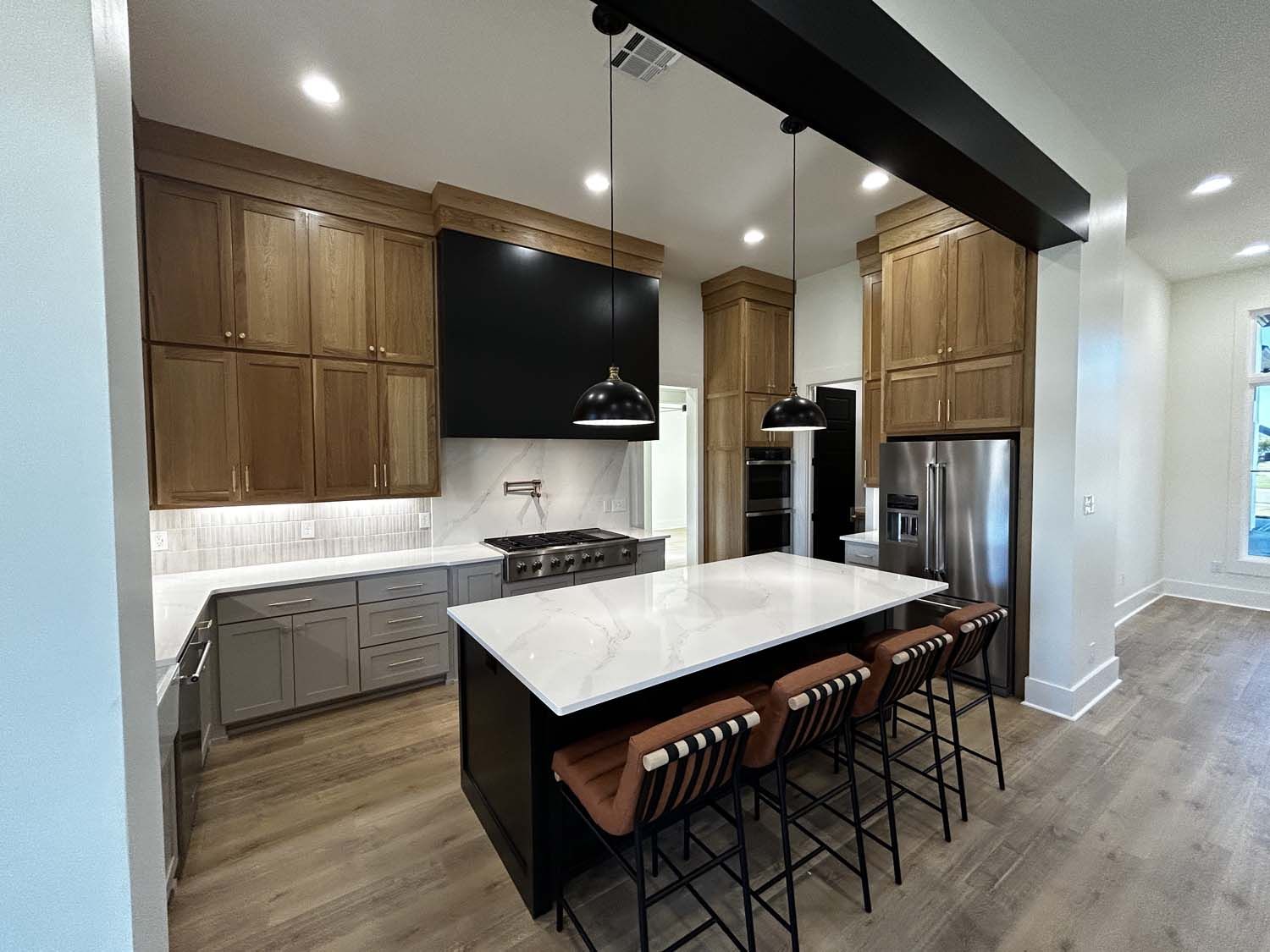 Modern kitchen with wood cabinets, gray island, stainless steel appliances.
