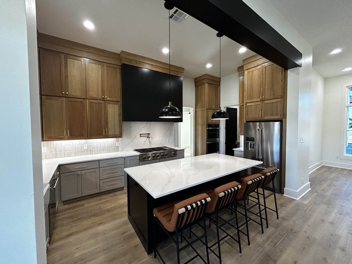Modern kitchen with wooden cabinets, gray island, and stainless steel appliances.