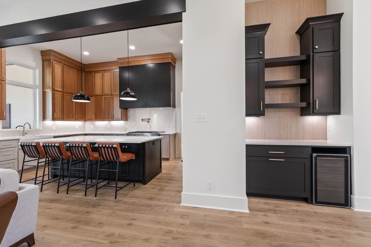 Modern kitchen with dark island and cabinetry, light wood floors, and bar seating.