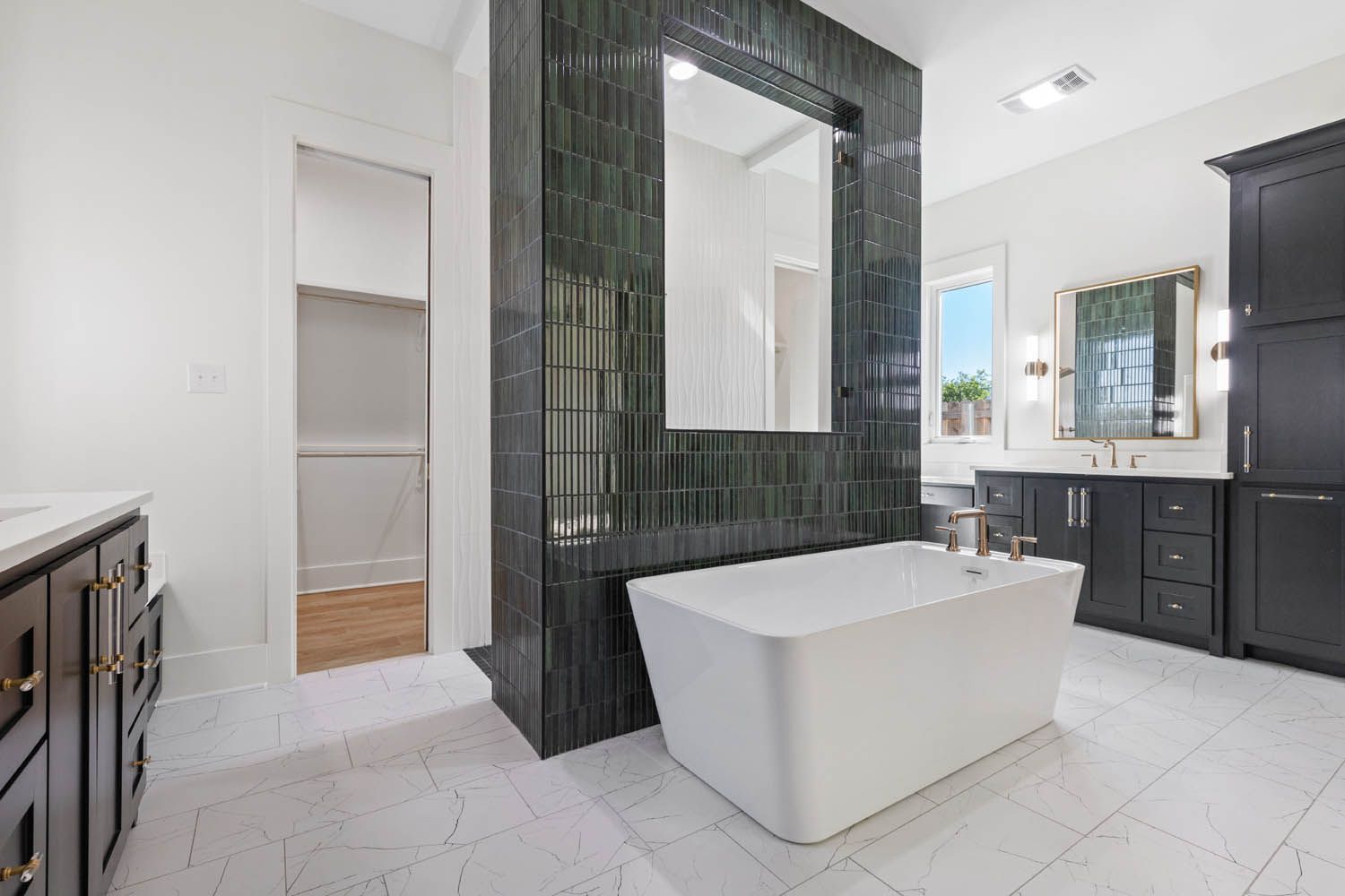 Modern bathroom with a white tub, black cabinets, and dark green tiled wall with a mirror.
