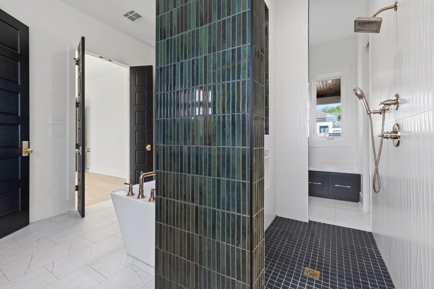 Bathroom with teal tile pillar, black doors, white tub, and walk-in shower.
