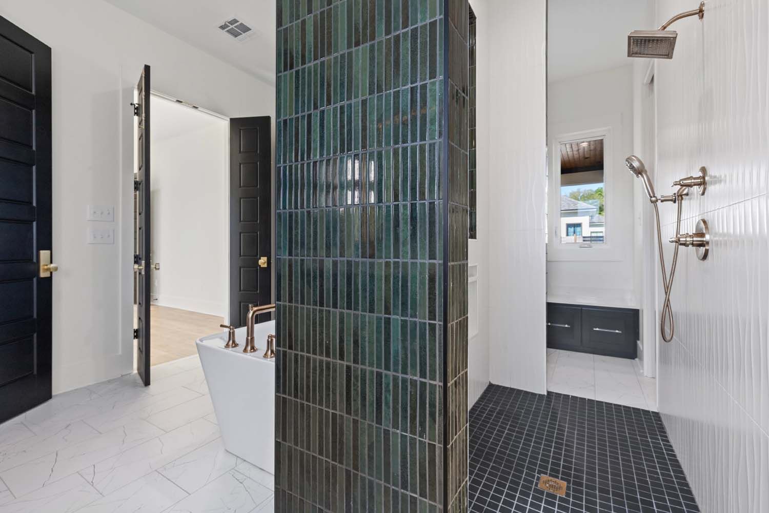 Luxurious bathroom with dark teal tile, black door, and white tub.
