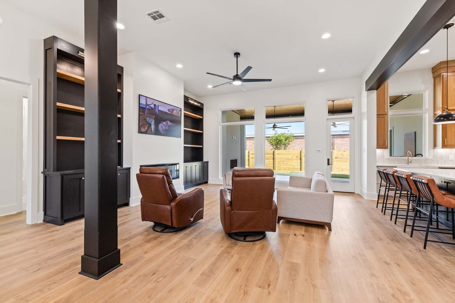 Living room with wooden floors, black bookshelves, and seating.