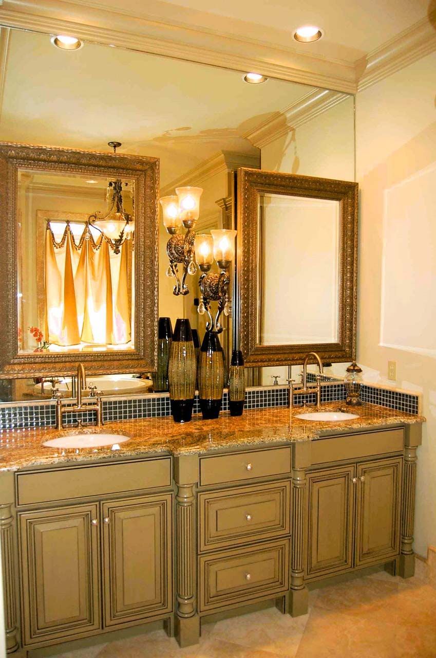 Bathroom with gold-framed mirrors over a double vanity with a speckled countertop and decorative vases.