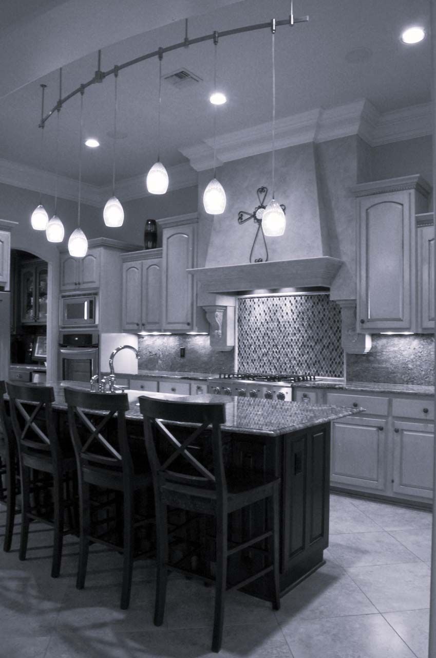 Modern kitchen with island, pendant lights, and stainless steel appliances.