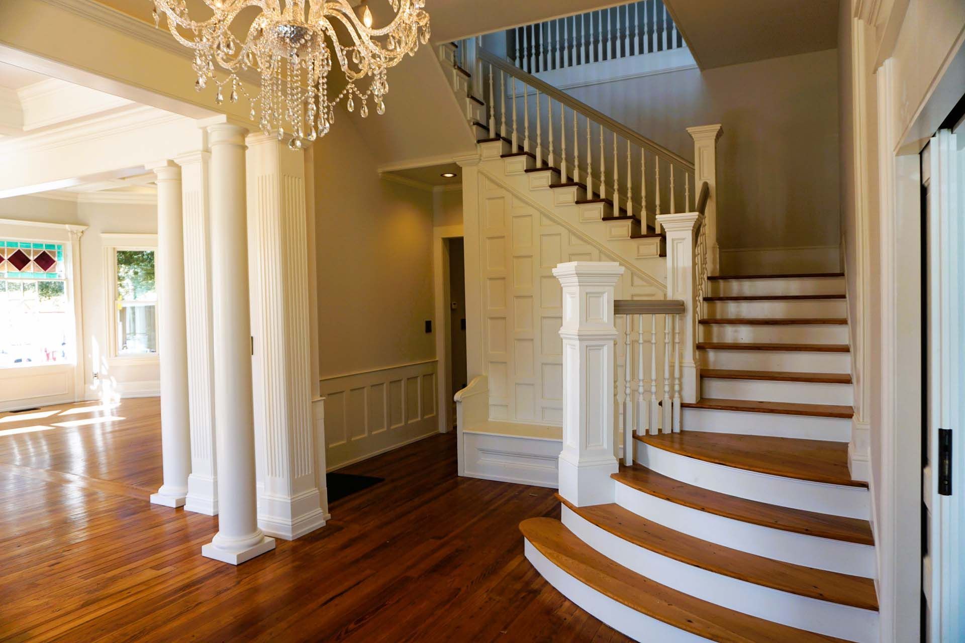Elegant foyer with a winding staircase, hardwood floors, and ornate chandelier.