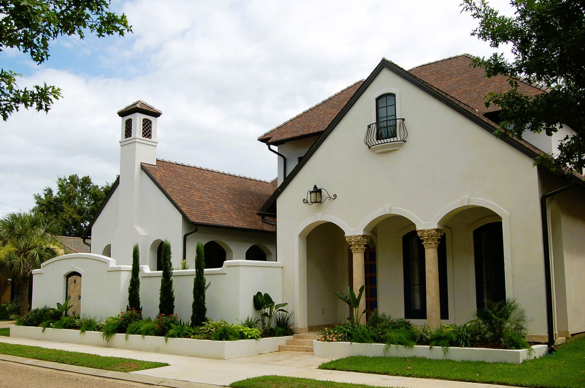 White stucco house with terracotta roof, arched porch, and small bell tower.