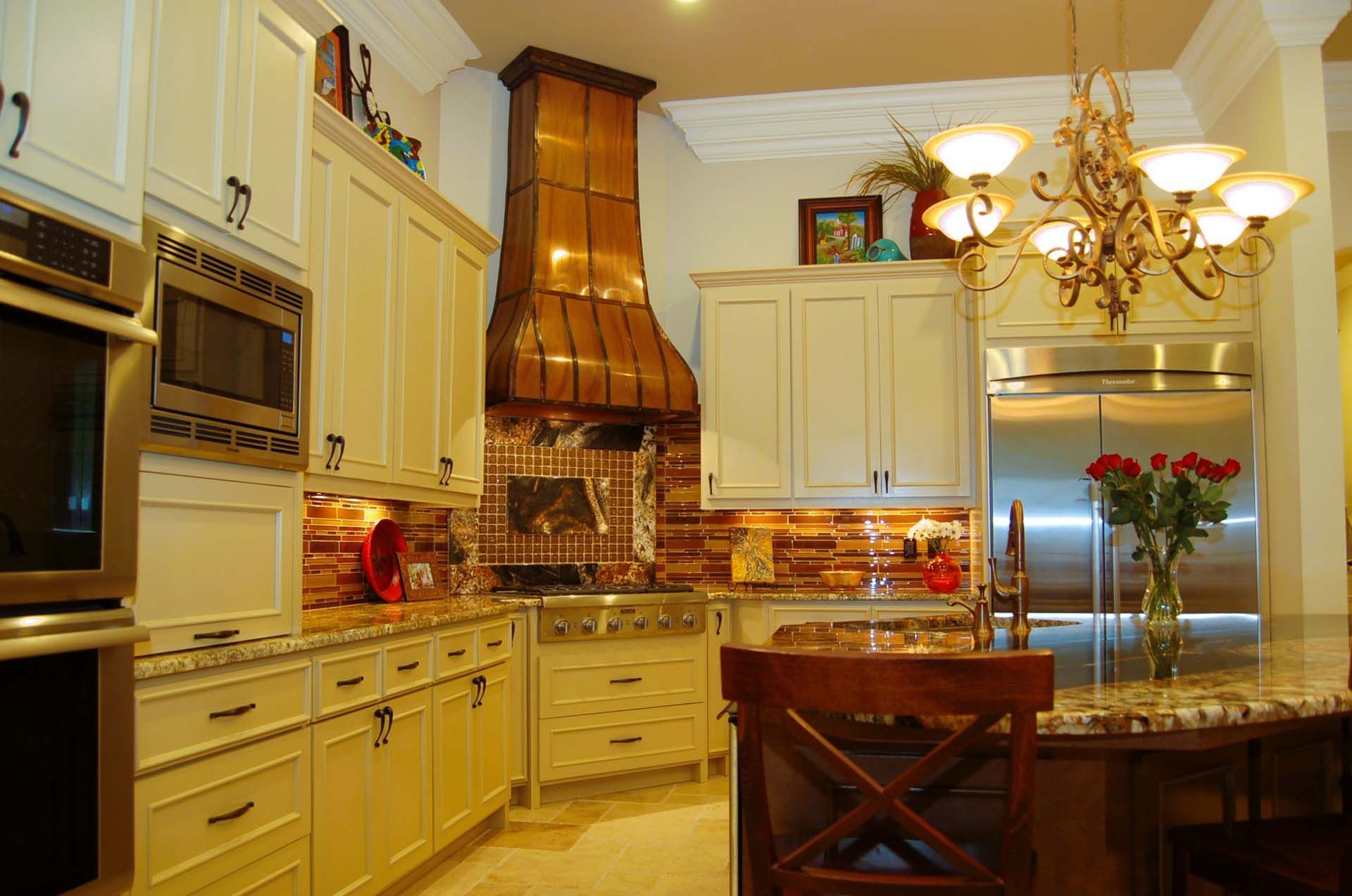 Cream-colored kitchen with copper range hood, stainless steel appliances, and granite countertops.