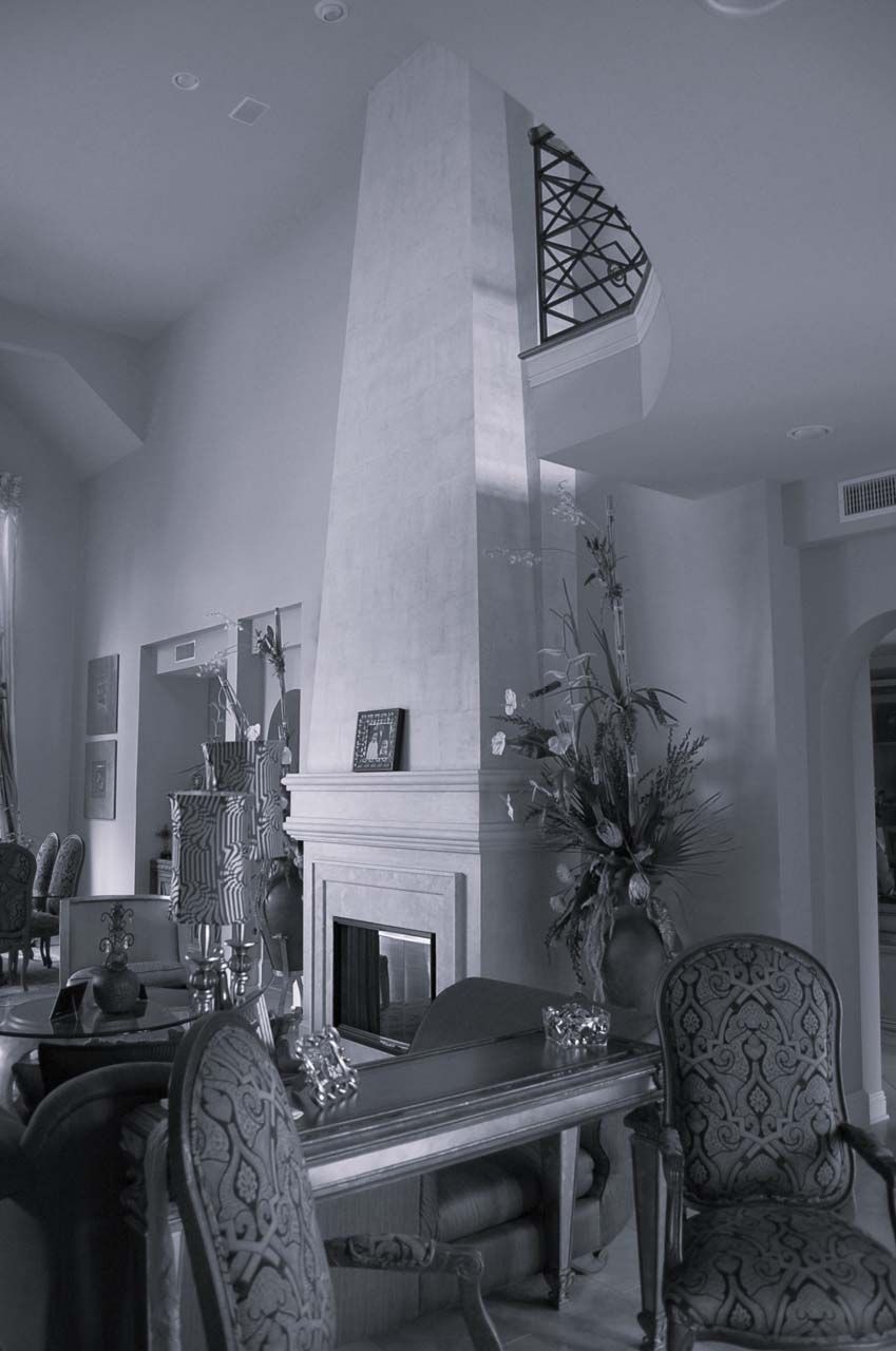 Elegant living room with tall fireplace, table, chairs, and decorative items.