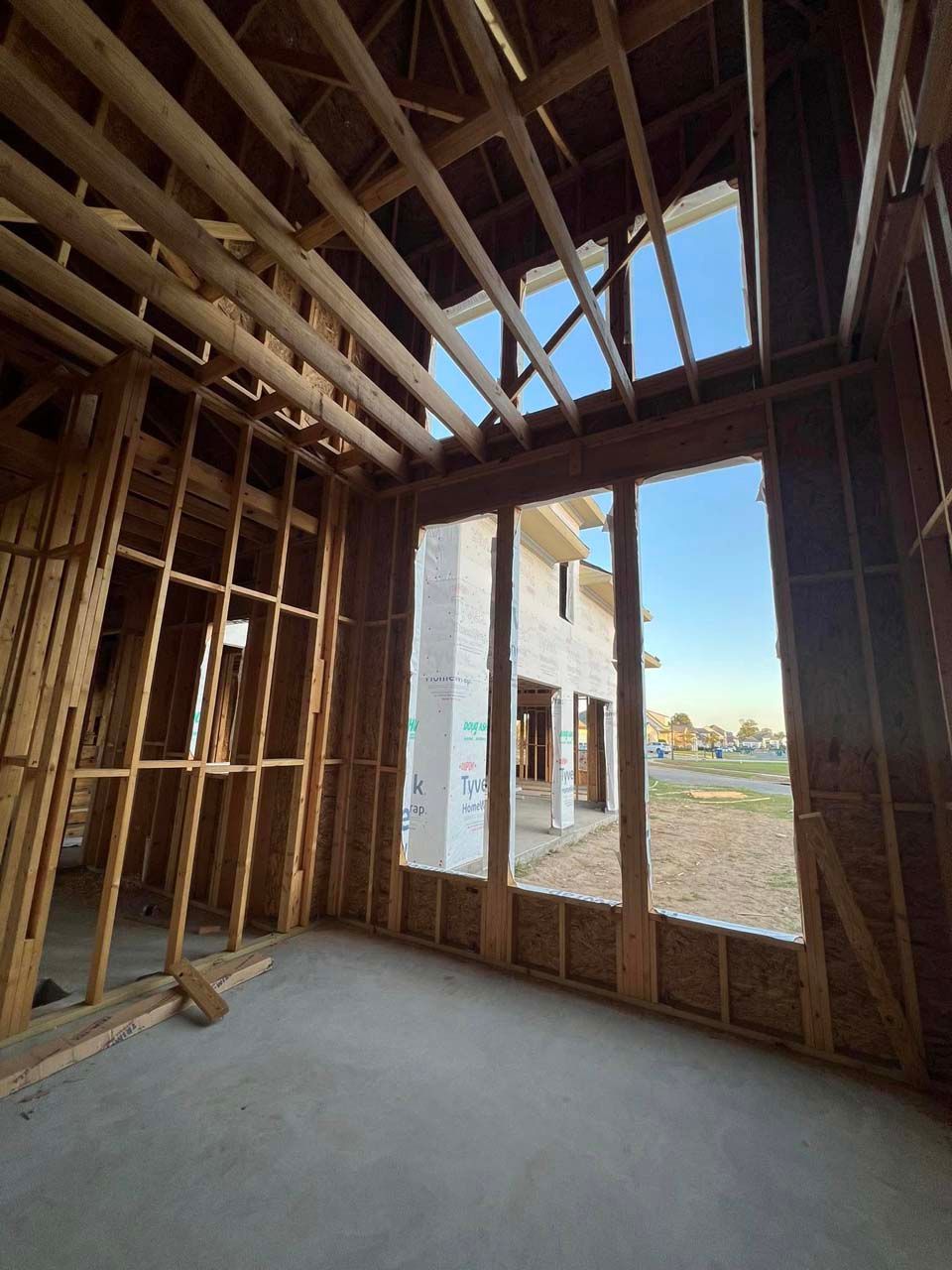 Interior view of a building under construction, showing wooden framing and window to the exterior.