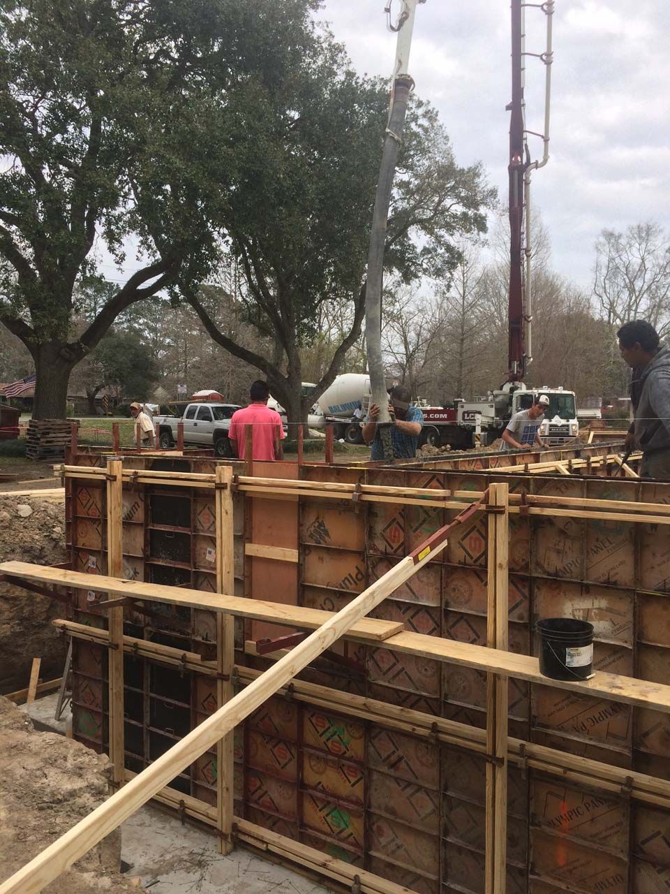 Construction workers pouring concrete into wooden forms. A concrete pump is visible.