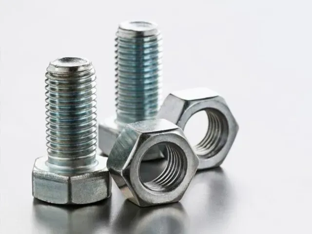 Un primer plano de tuercas y tornillos sobre una mesa.