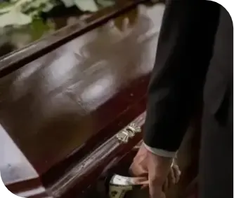 Hand placing a gold handle on a dark wooden coffin in a funeral setting