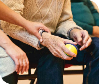 Hands of two people holding a yellow ball during an indoor activity.