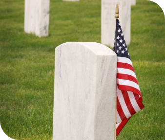 American flag beside a white gravestone in a grassy cemetery