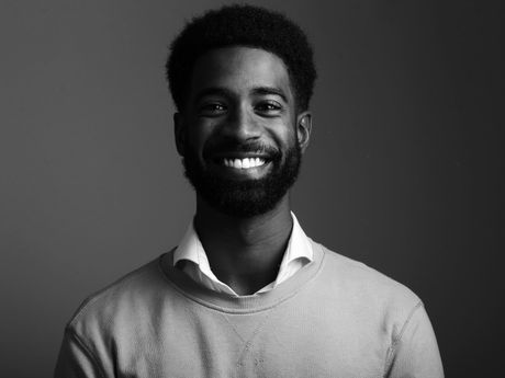 A man with a beard is smiling in a black and white photo.