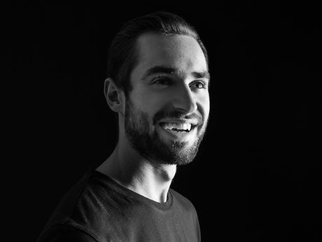 A man with a beard is smiling in a black and white photo