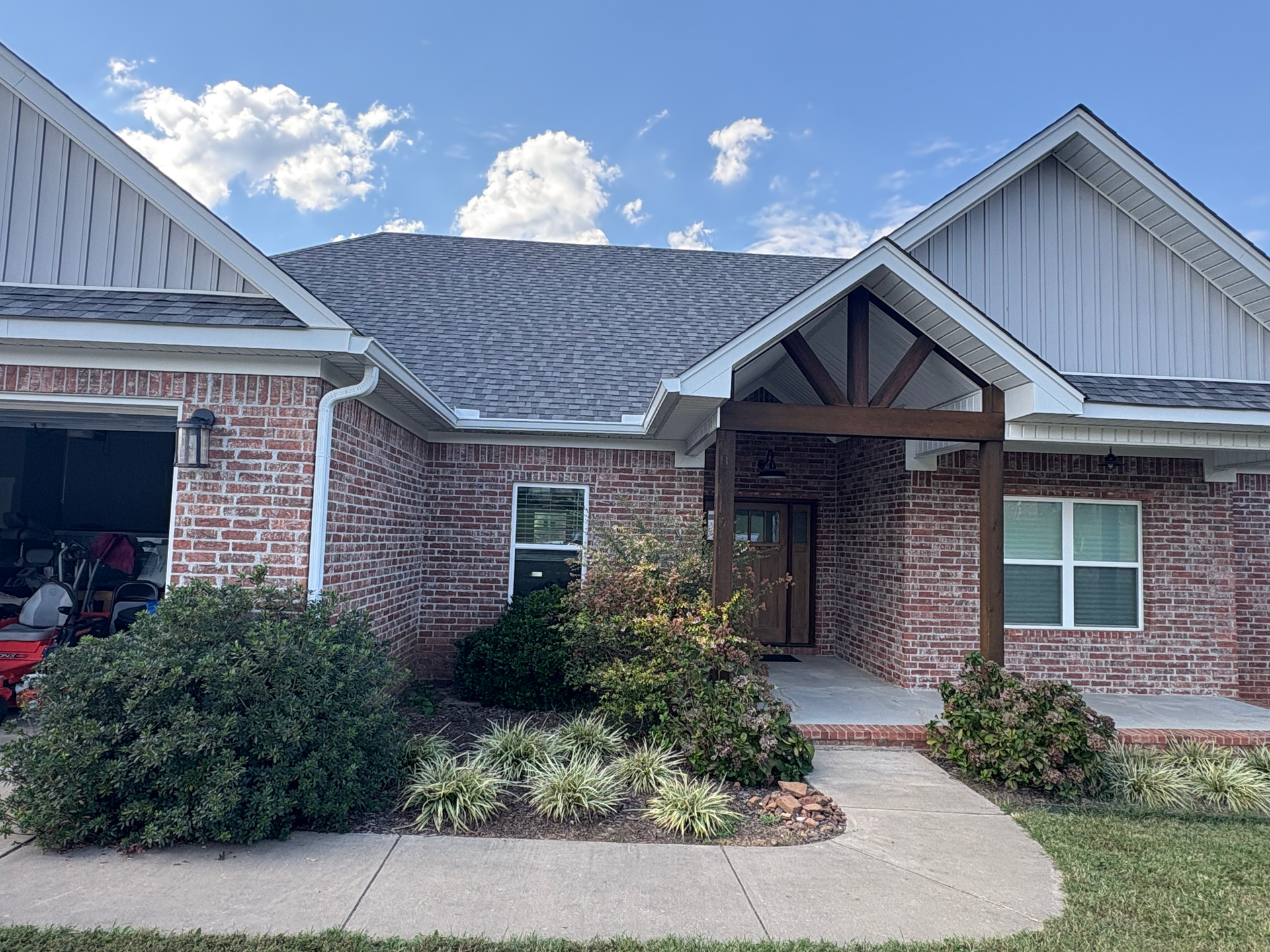 Single-story brick house with a covered front porch, a gray roof, and a sidewalk leading to the entrance.