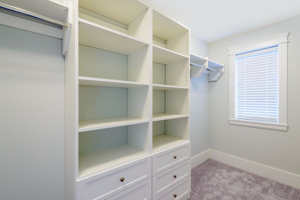 A Walk in Closet With Lots of Shelves and Drawers and a Window — Wardrobe World In Paget, QLD