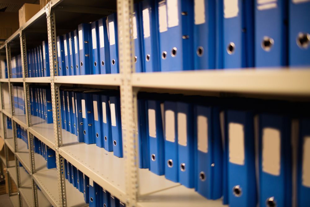 A Row of Shelves Filled With Blue Binders in a Warehouse — Wardrobe World In Paget, QLD