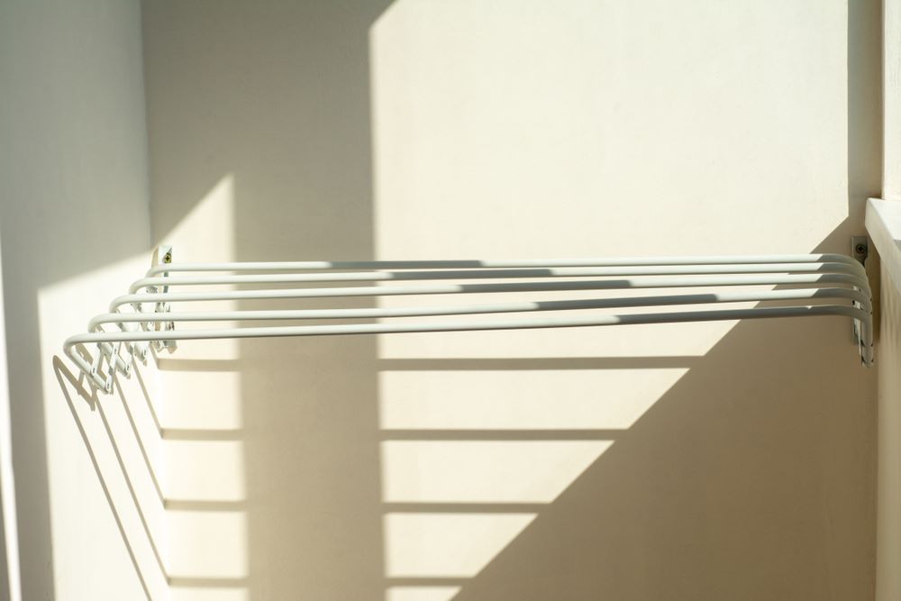 A Clothes Drying Rack is Hanging on a Wall Next to a Window — Wardrobe World In Paget, QLD