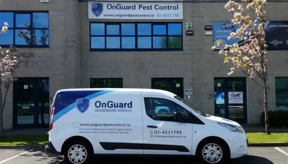 A white van is parked in front of a building that says onguard pest control.