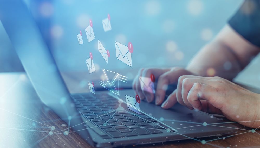 Hands typing on a laptop with glowing digital icons floating above the keyboard.