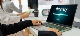Person using a laptop showing “Recovery” in a bright office setting