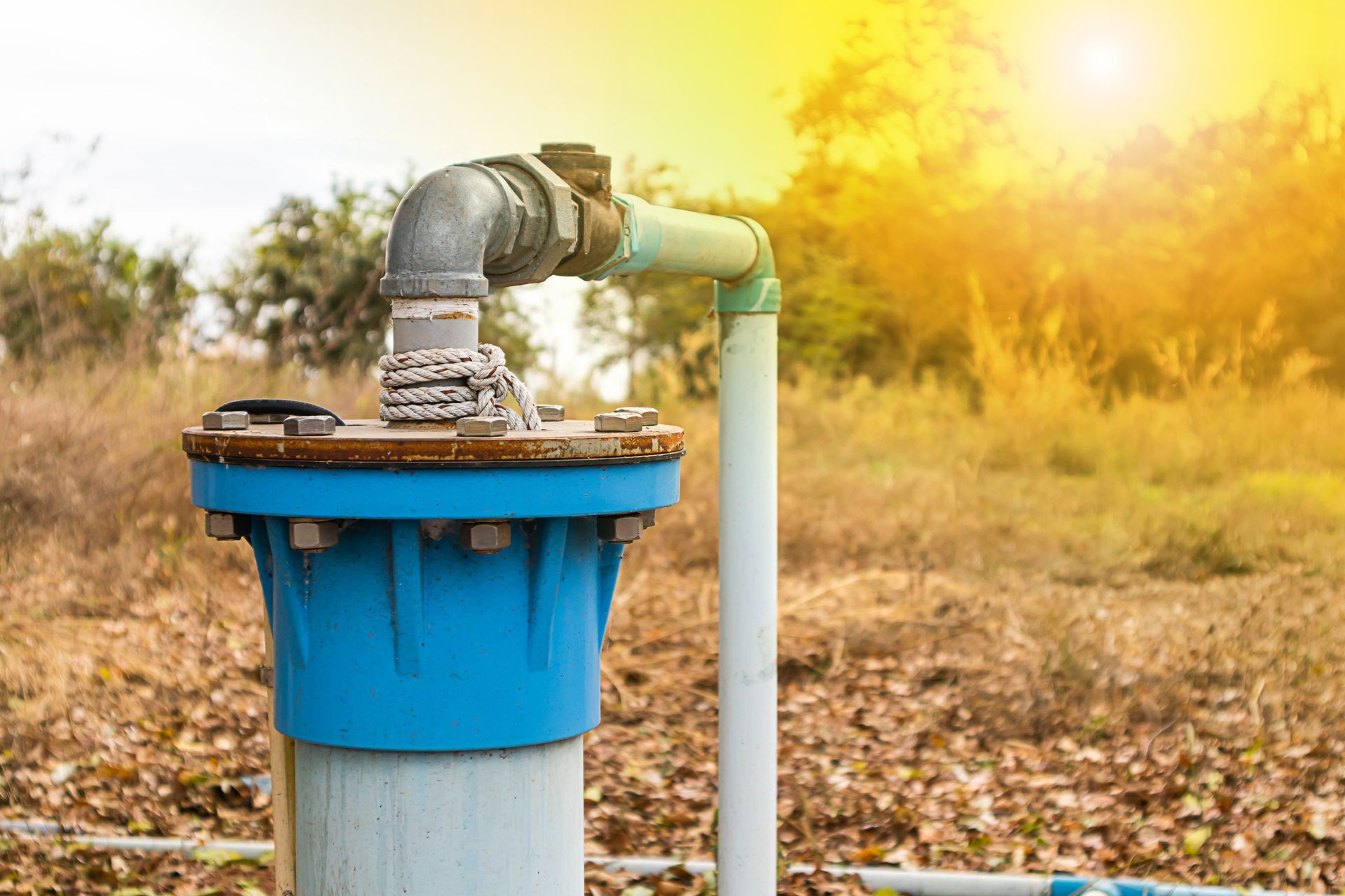 Blue water well pipe with faucet in a sunny field Blue water well pipe with faucet in a sunny field
