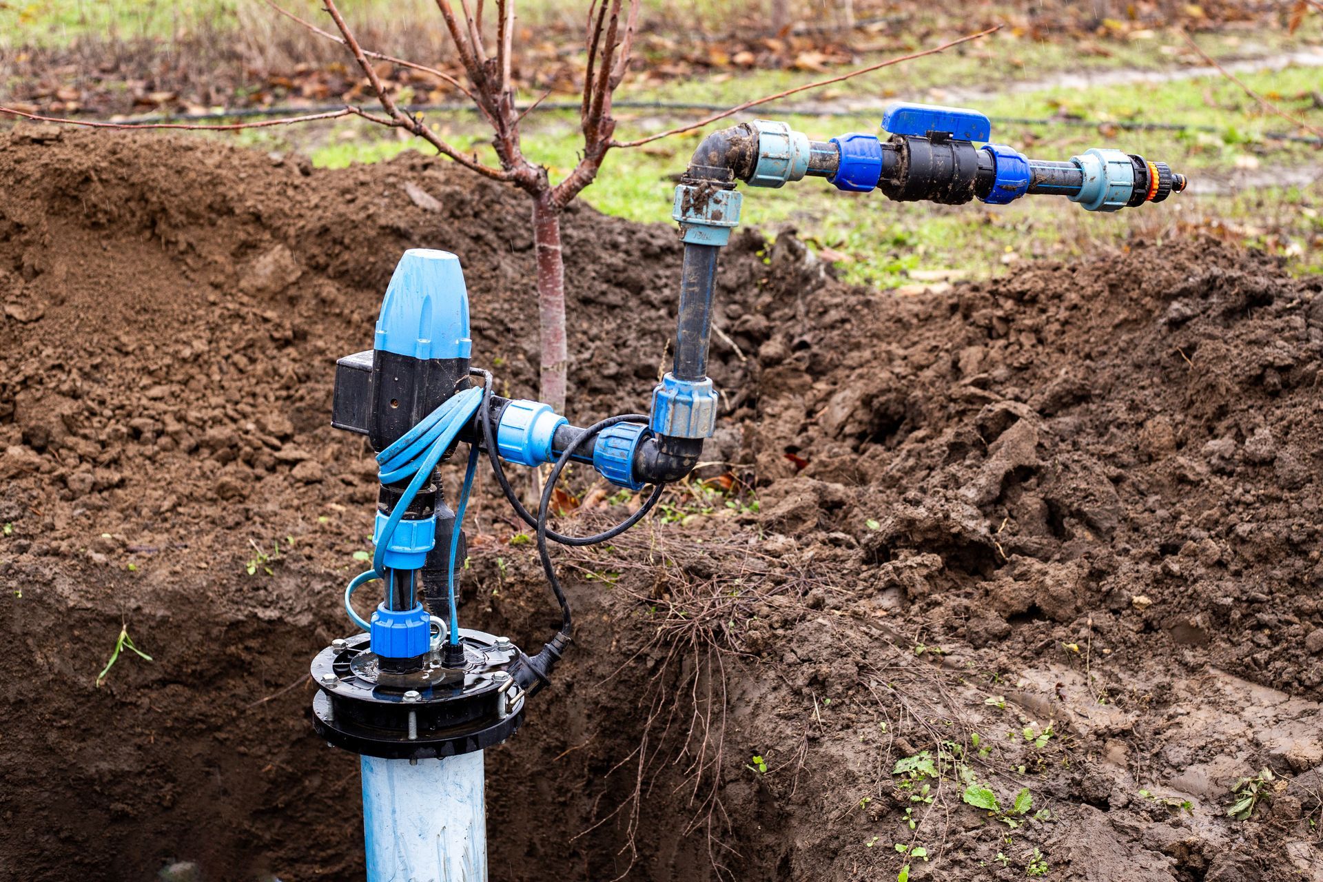 Blue irrigation pipe and sprinkler valve assembly in a muddy field. Blue irrigation pipe and sprinkler valve assembly in a muddy field.
